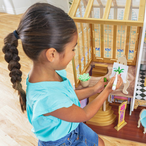 little girl kneeling in front of kidkraft dollshouse
