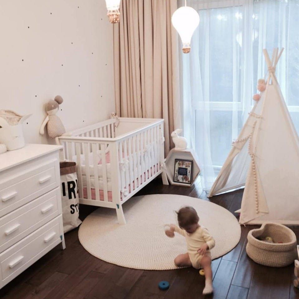 child sitting on rug in bedroom with MINICAMP Original Play Tent With Pompoms