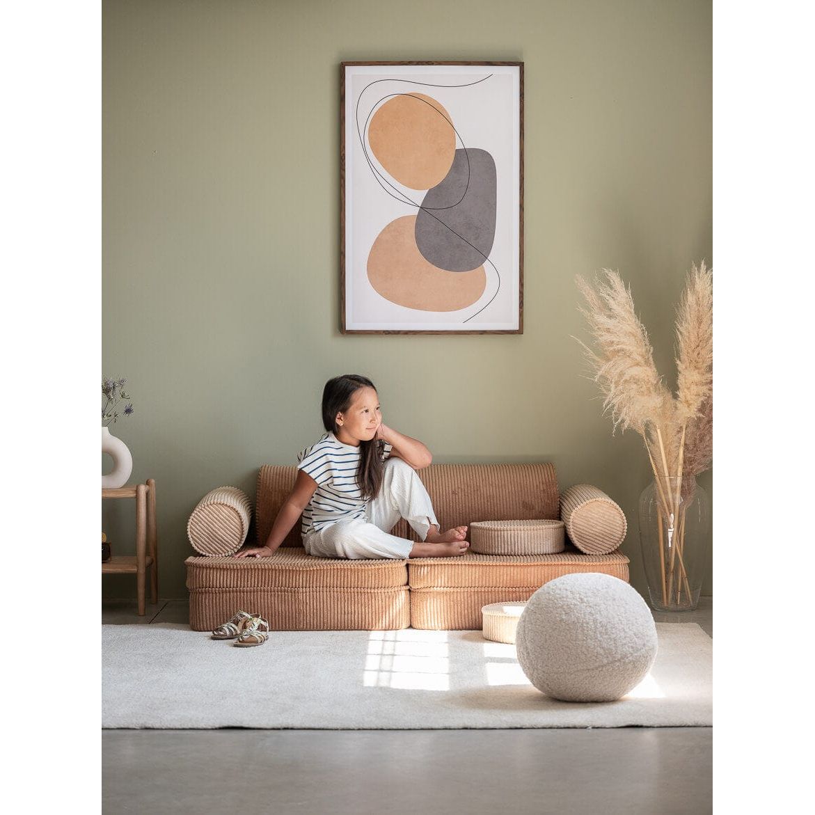 girl sitting on Wigiwama Toffee Settee in lounge in fornt on wall art