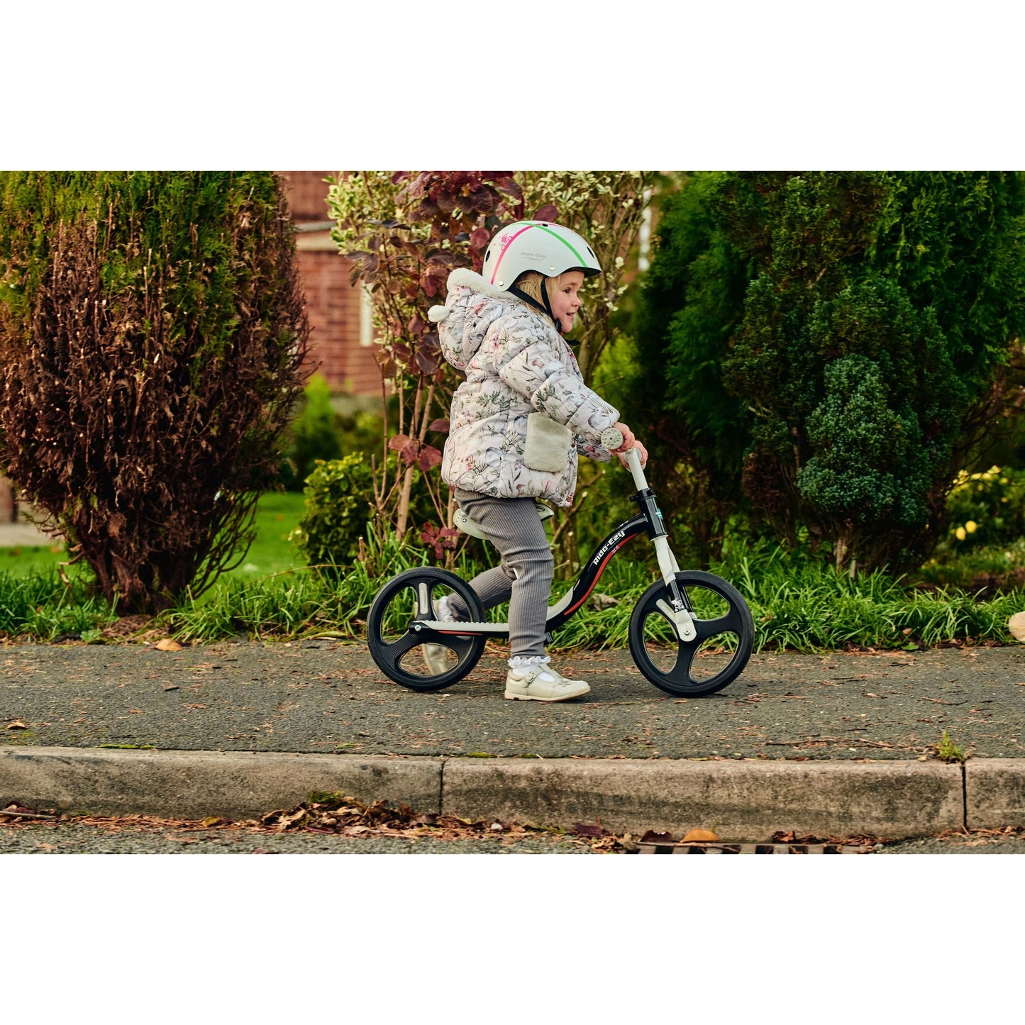 side view of girl riding Ride-Ezy Go Glo Balance Bike - Black & Silver