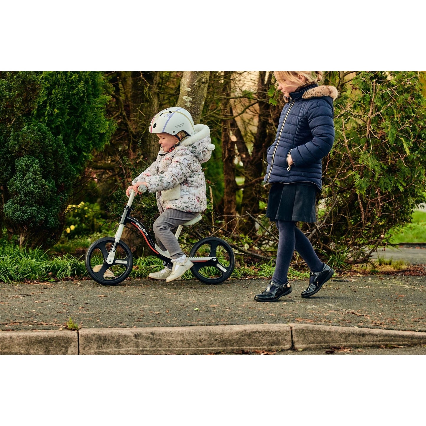 girl wearing Ride-Ezy Hector 54-57cms Kids Helmet - White and riding ride-ezy go glo balance bike