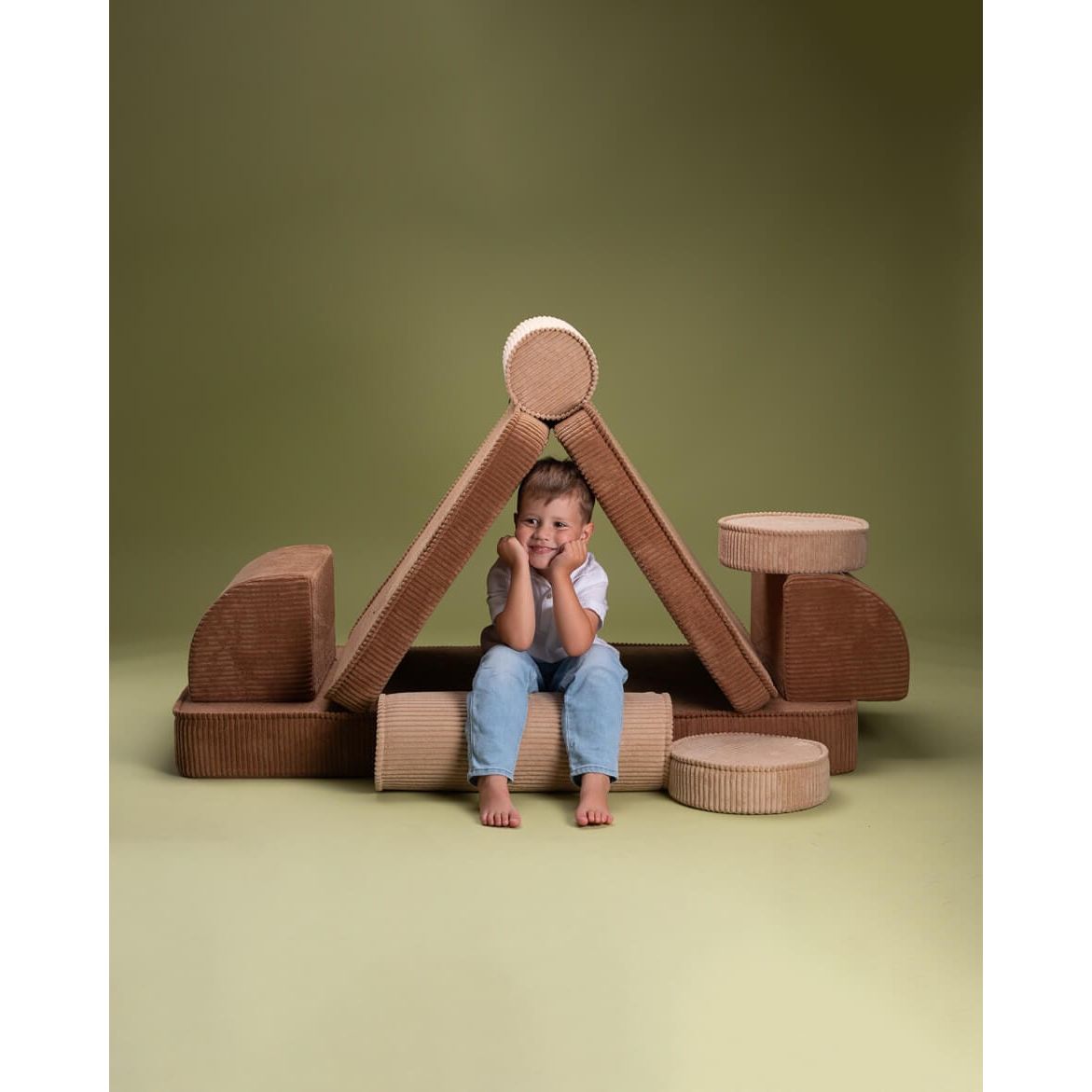 boy sitting under cushions of Wigiwama Toffee Settee