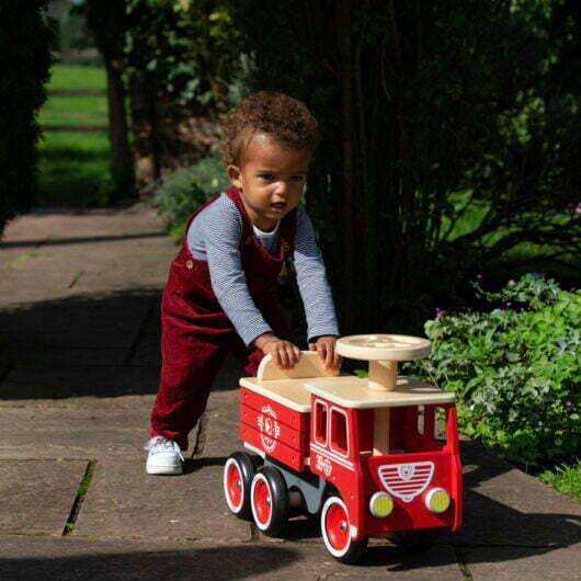 boy pushing vilac wooden ride on firetruck