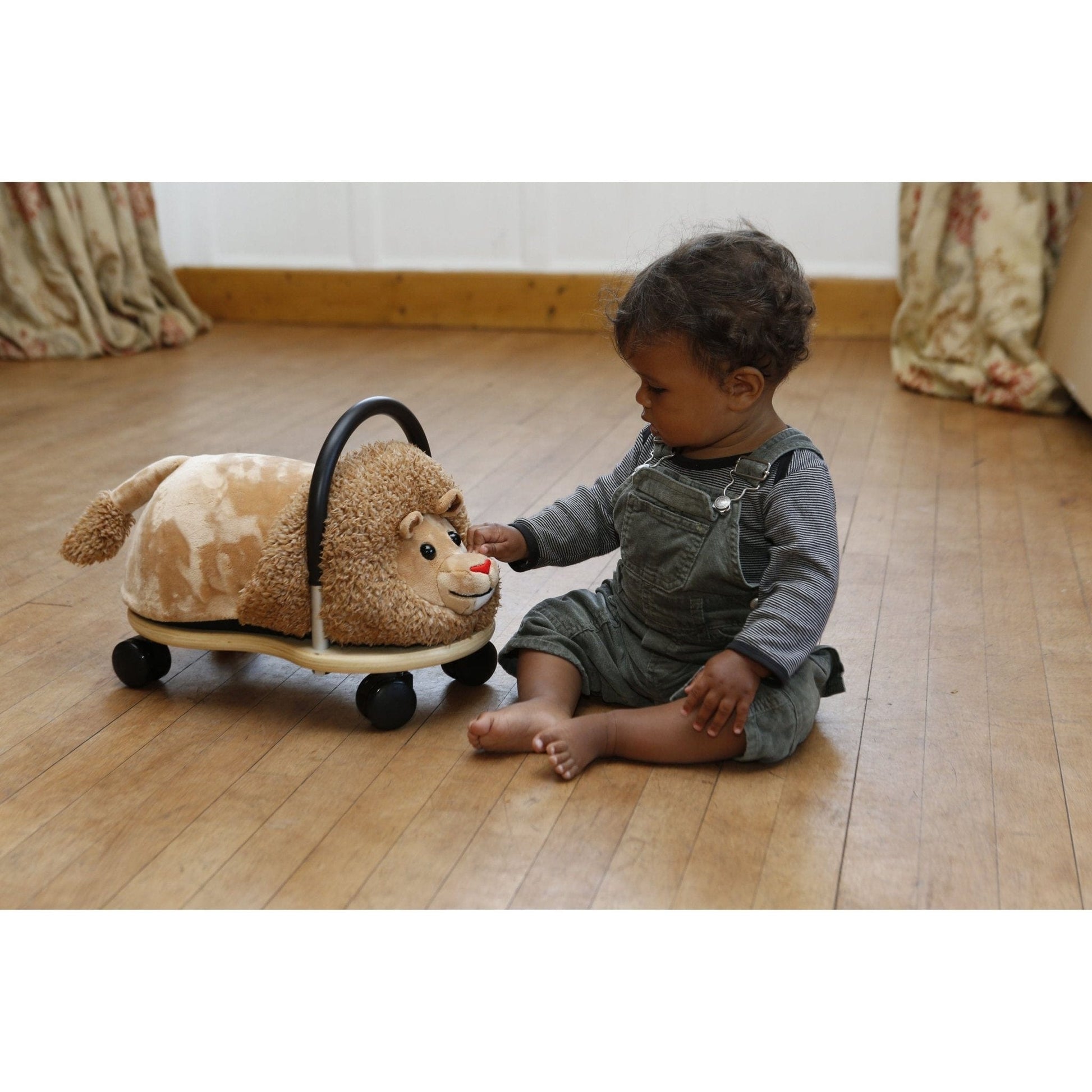 girl sitting on floor stroking Wheelybug Plush Ride On - Lion