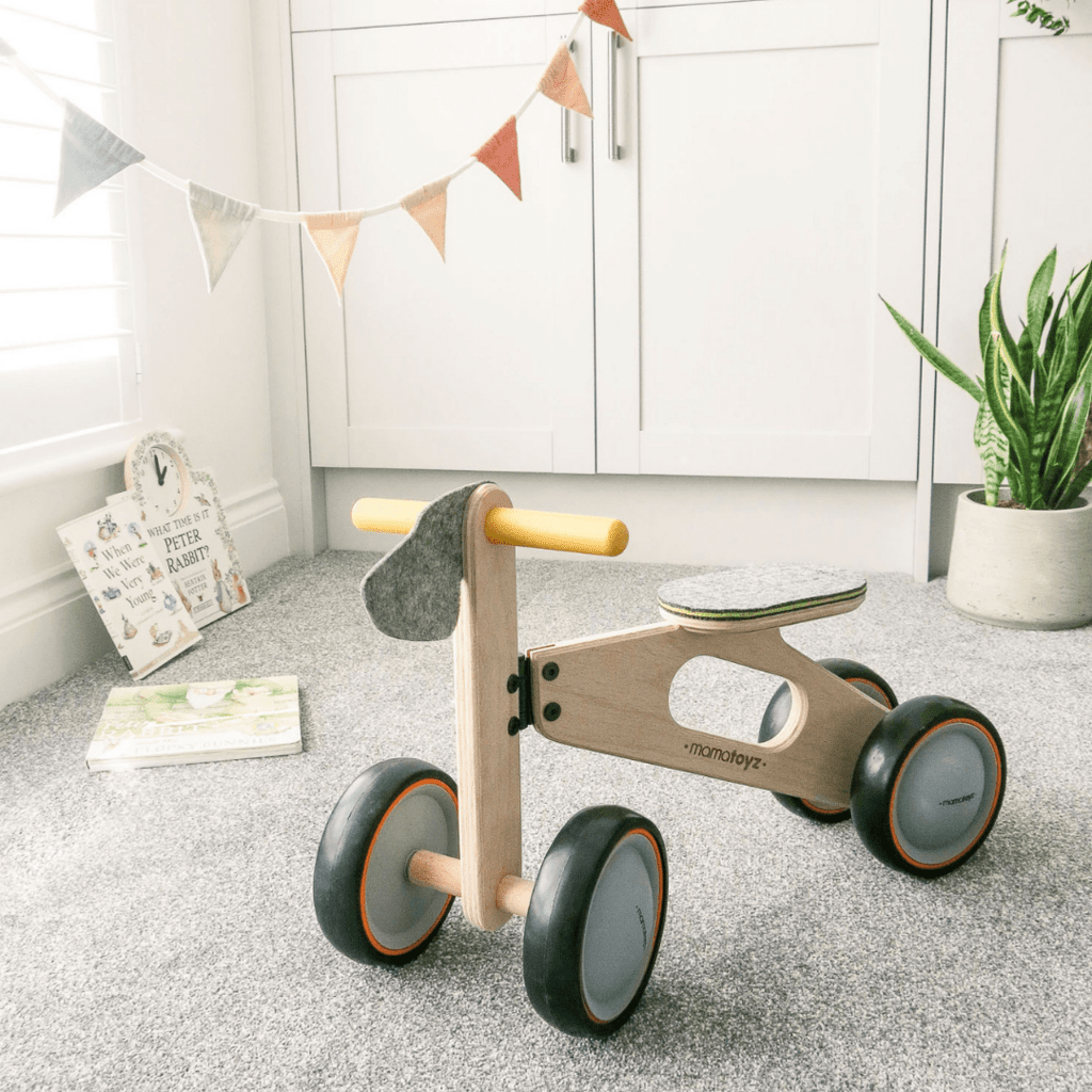 Mama Toyz Wooden Mini Bike Age 15 Months + in playroom, infront of cupboards