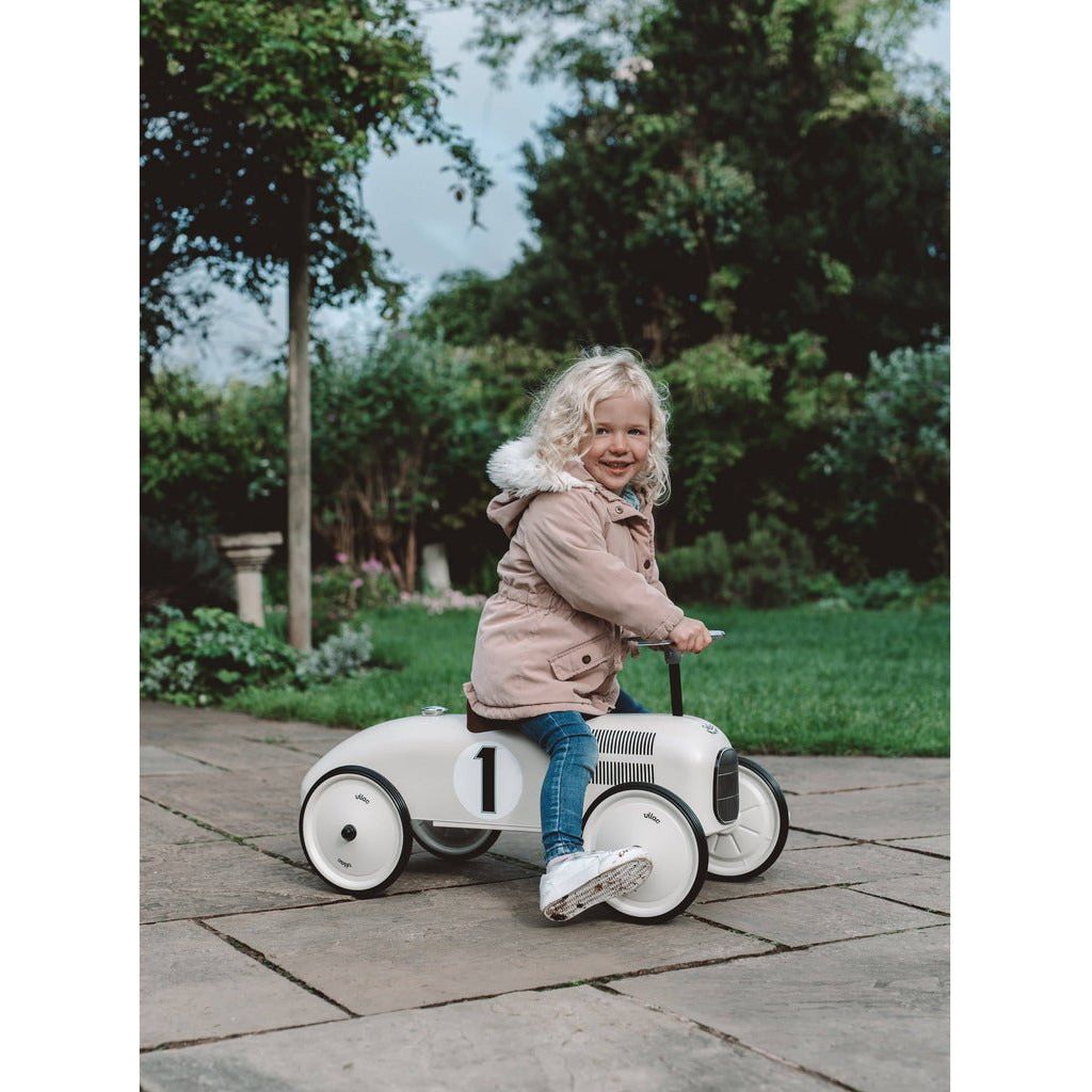 little girl riding Vilac Classic Ride-On Racing Car - 18m+ - Off White on patio