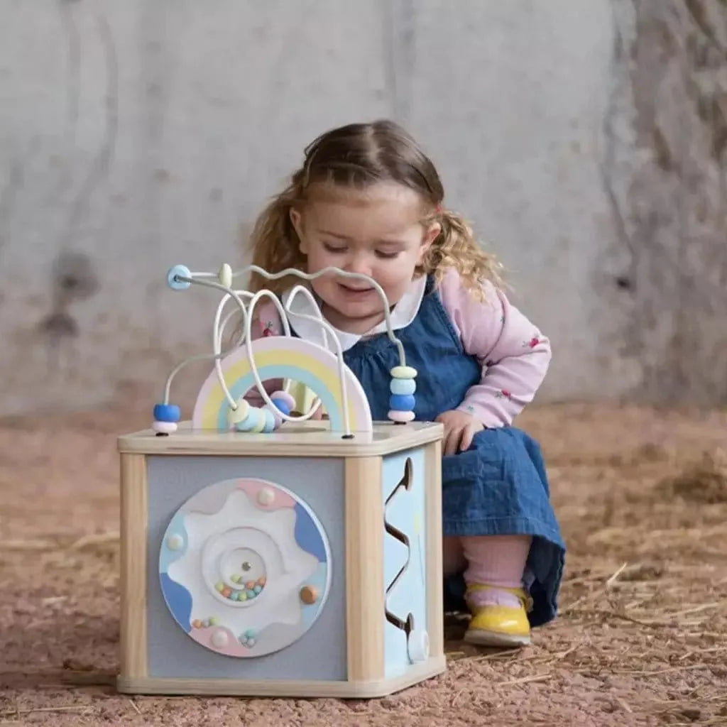 little girl kneeling next to Classic World Wooden Dream Activity Cube