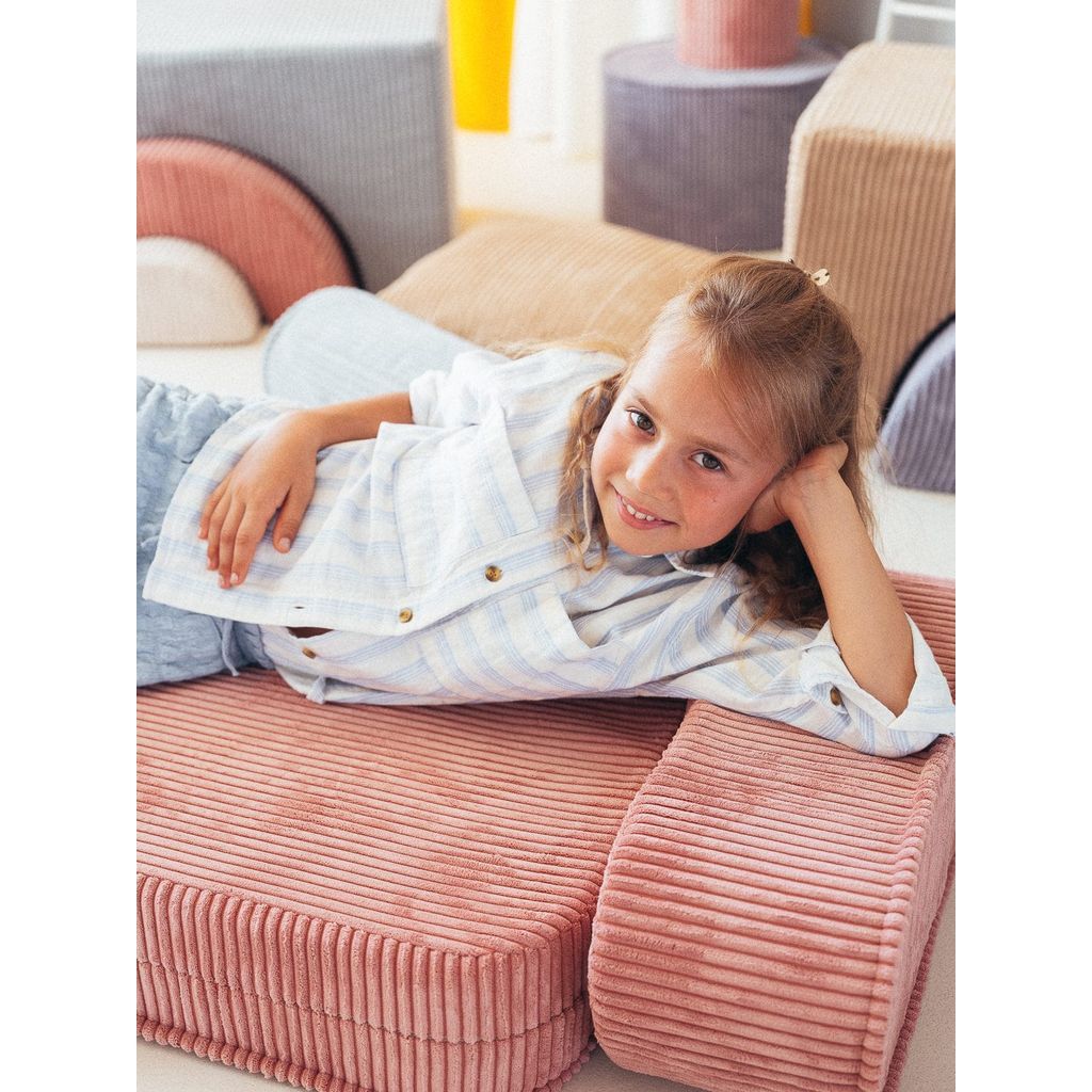 smiling girt lying on Wigiwama Pink Mousse Kids Flip Chair