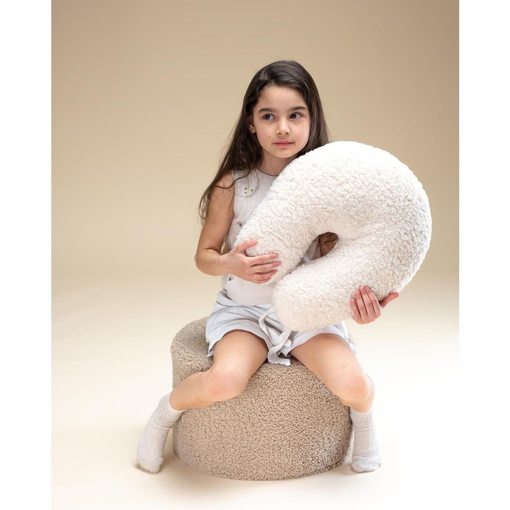 girl sitting on pouffe holding Wigiwama Cream White U Pillow