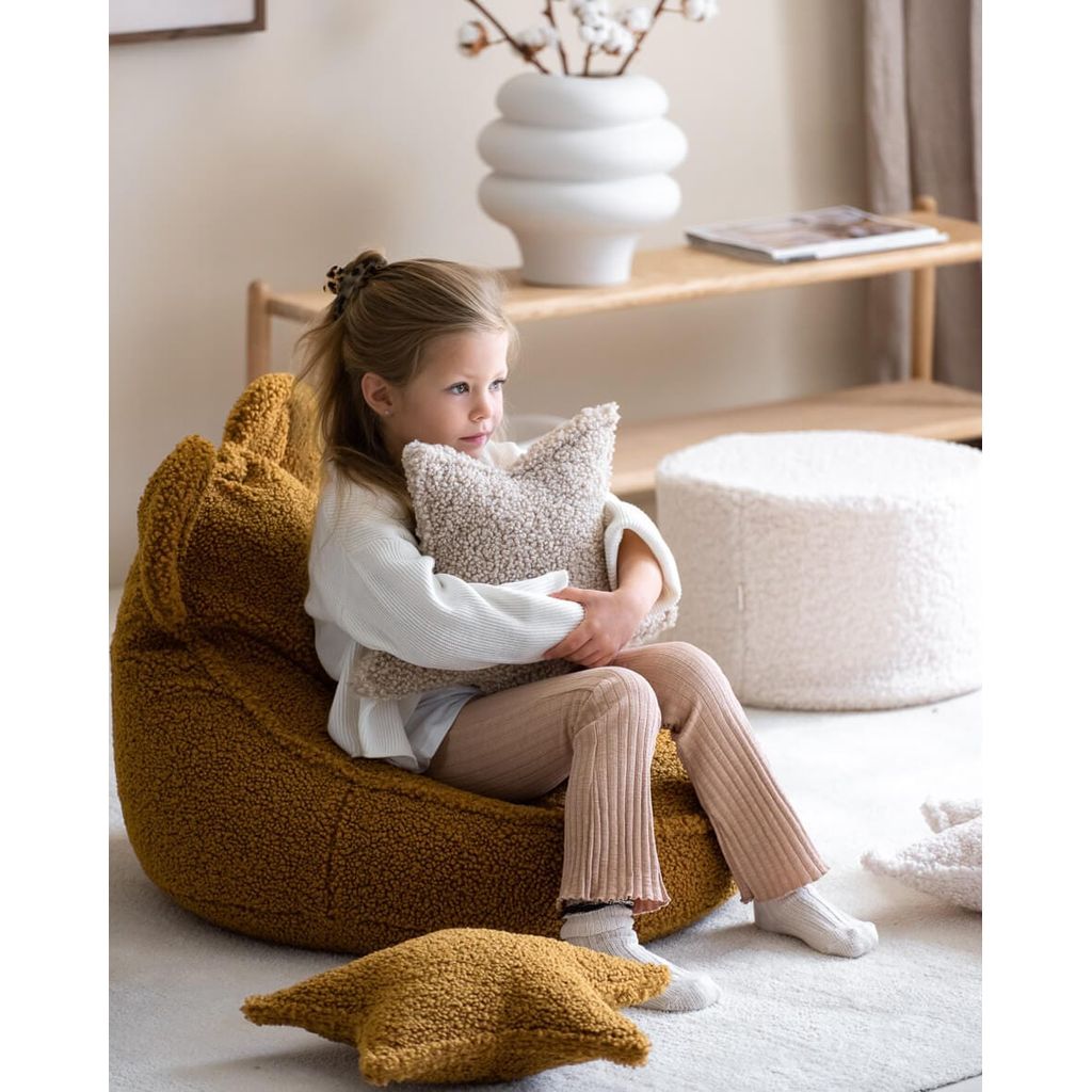 girl holding Wigiwama Maple Star Cushion while sitting on teaddy bear chair