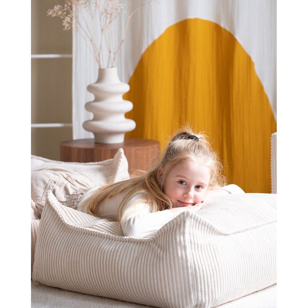 close up of girl lying on Wigiwama Marshmallow Square Ottoman and kids beanbag chair