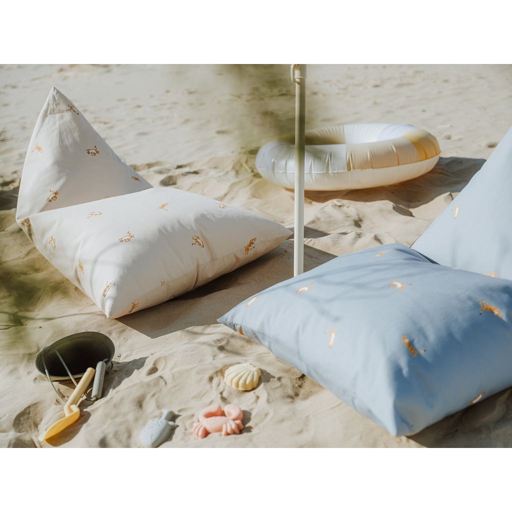 Wigiwama Beige Tiger Big Lounger next to blue cusion on the beach
