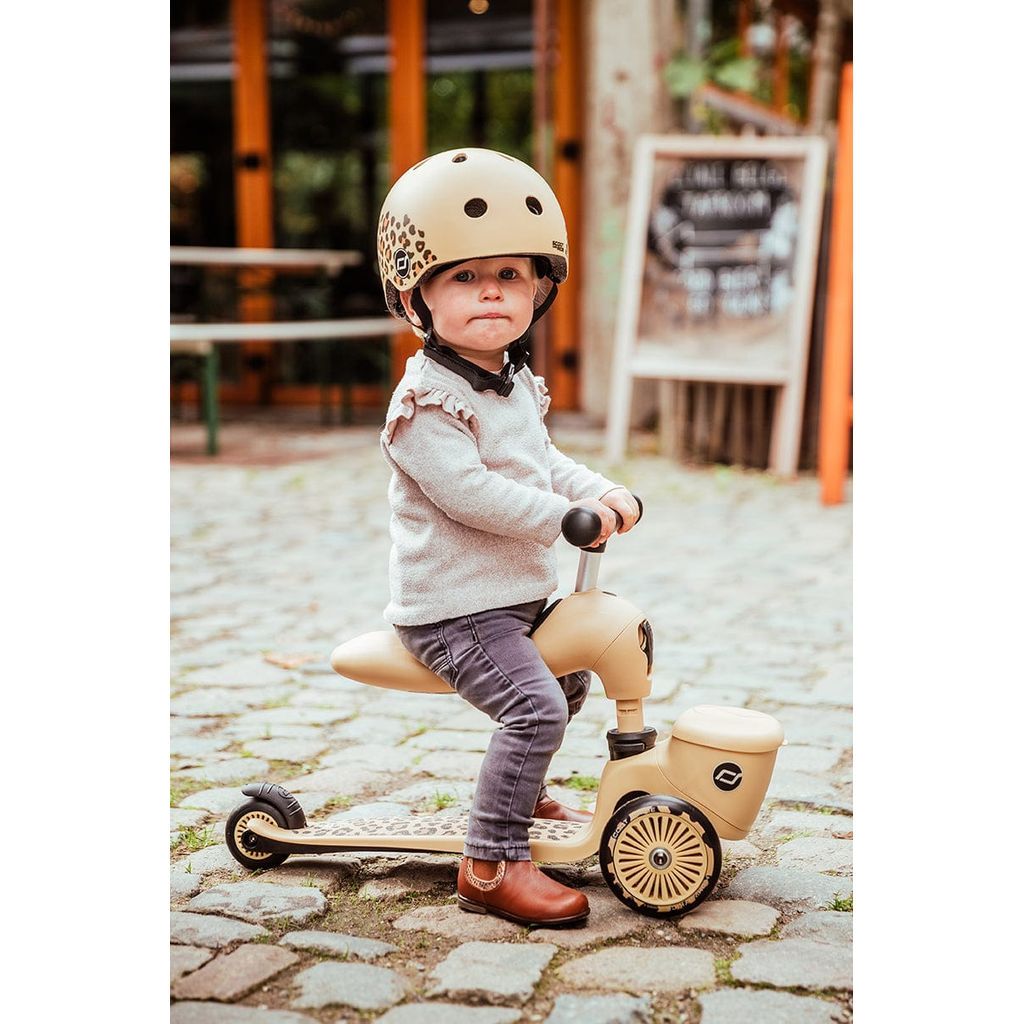 girl sitting on Scoot and Ride Highwaykick 1 Lifestyle Scooter - Leopard on cobbled street