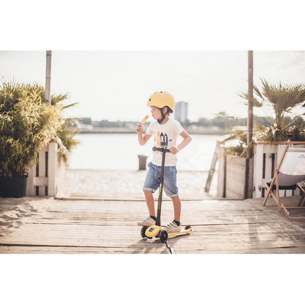 boy eating ice cream standing with Scoot and Ride Highwaykick 3 Scooter - Age 3+ - Led Lemon
