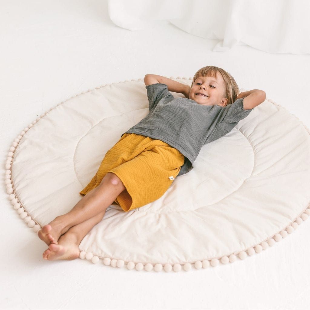 child lying on MINICAMP Kids Playmat With Pompom Border