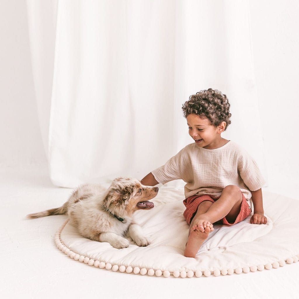 child and dog sitting on MINICAMP Kids Playmat With Pompom Border