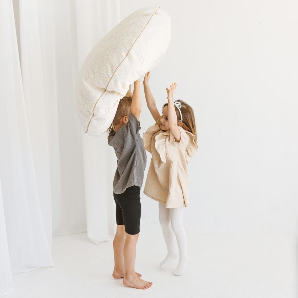 boy and girl holding MINICAMP Boucle Fabric Kids Floor Cushion in Ecru  in the air