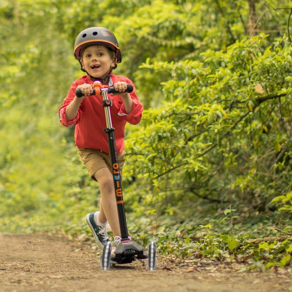 boy riding Micro Scooter Maxi Deluxe LED - Black in woods