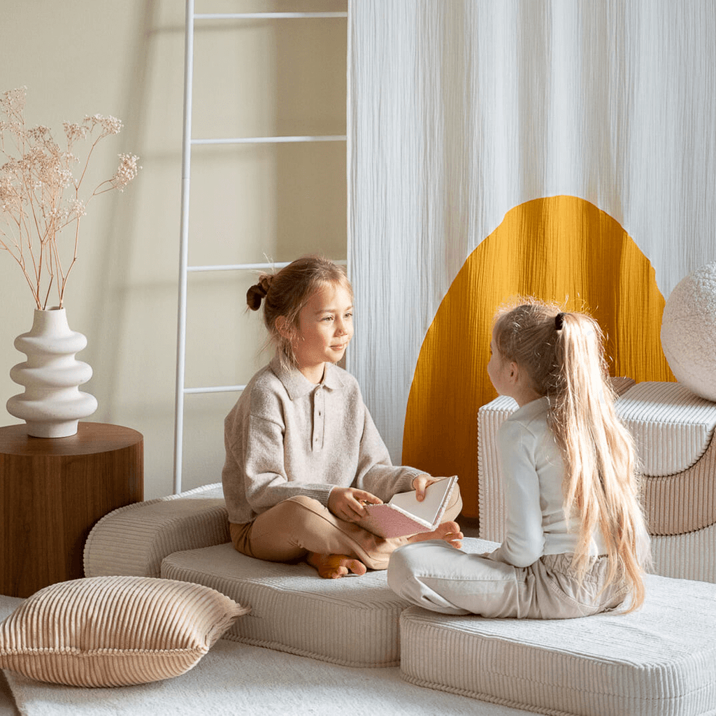 2 girls sitting opposite each other on Wigiwama kids furniture Marshmallow Flip Chair
