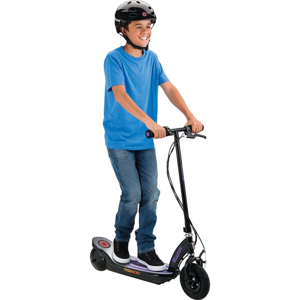 boy in helmet tsanding on Razor Power Core E100 24 Volt Scooter - Purple