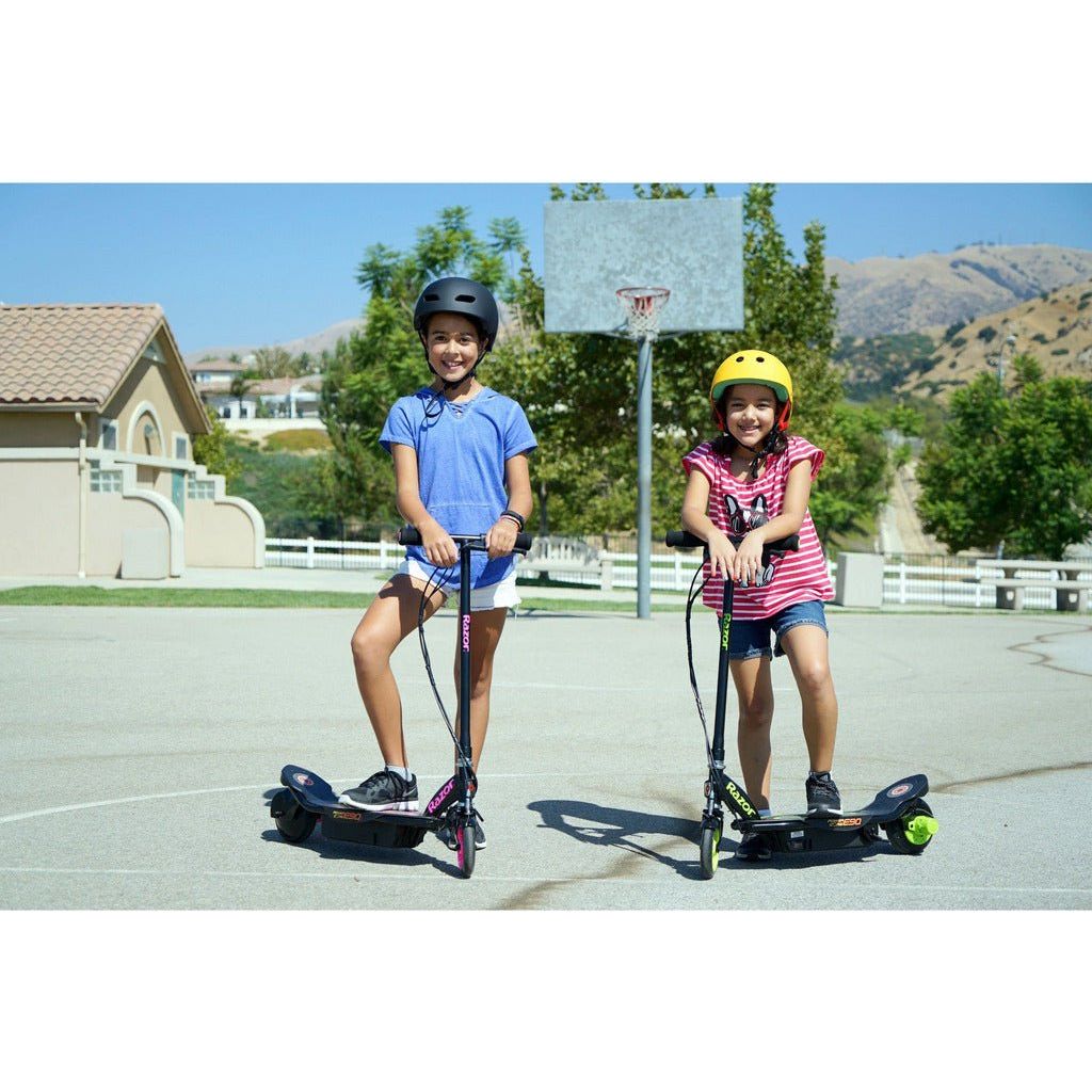 2 girls standing with Razor Power Core E90 12 Volt Scooters next to each other