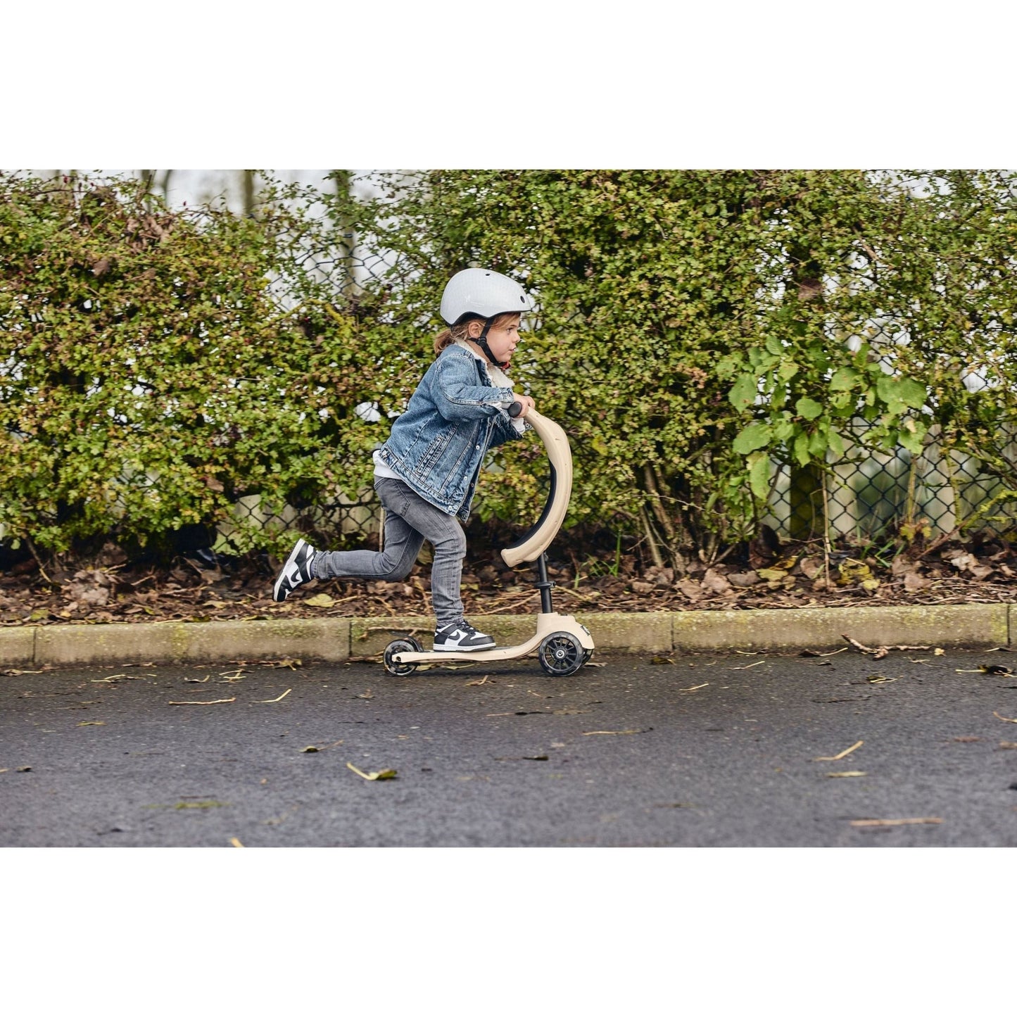 side view of girl riding ride-ezy scooter and wearing Ride-Ezy Hector 48-53cms Kids Helmet - Sandy