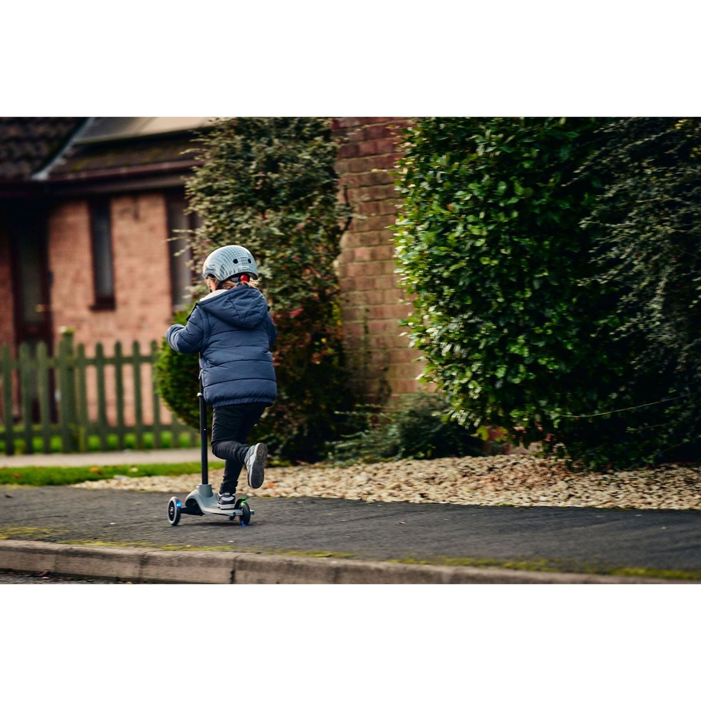 girl riding ride-ezy scooter and wearing Ride-Ezy Hector 48-53cms Kids Helmet - Thunder Clouds from behind