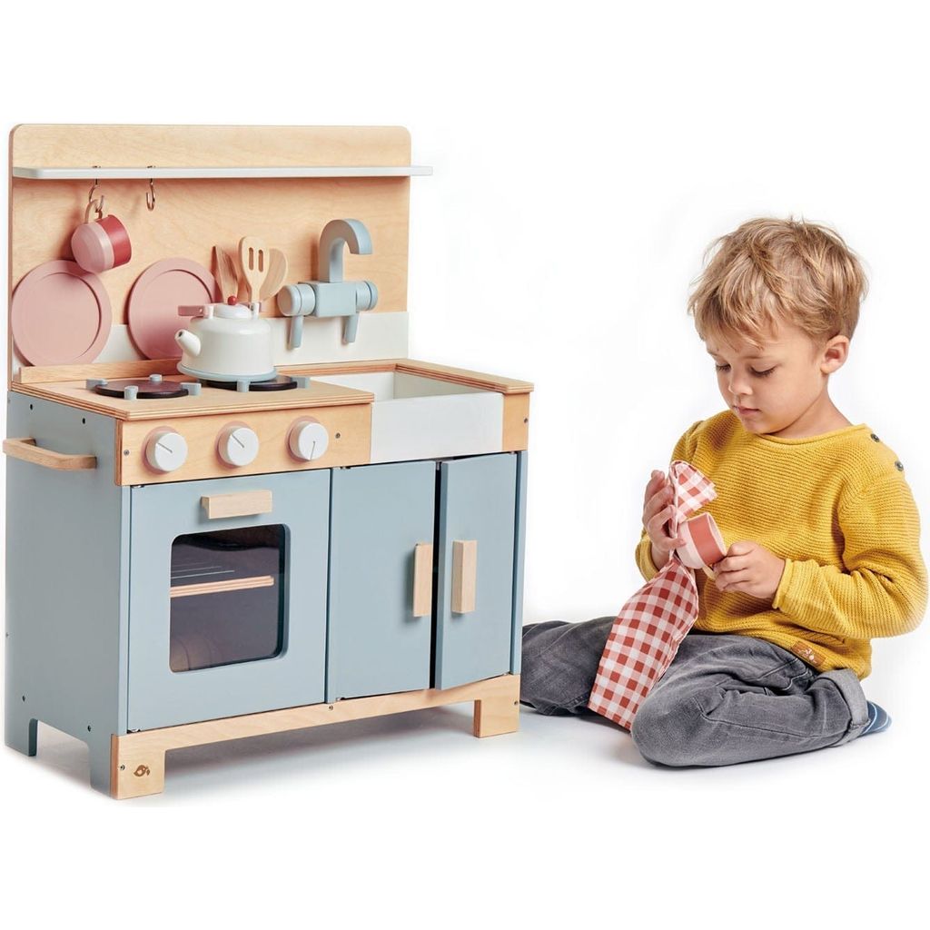 boy kneeling next to Tender Leaf Home Wooden Play Kitchen