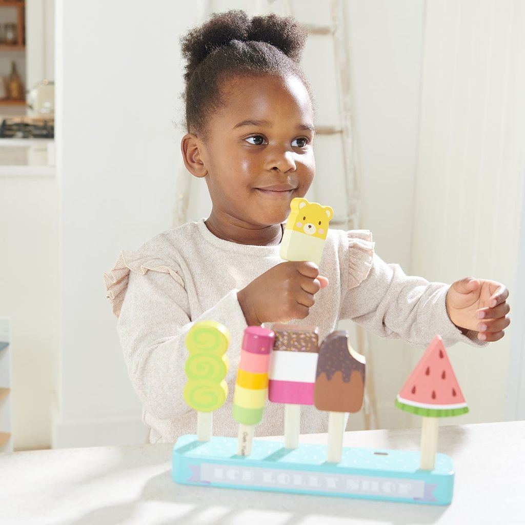 girl at table playing with Tender Leaf Rainbow Cake & Lolly Shop Wooden Toy Bundle