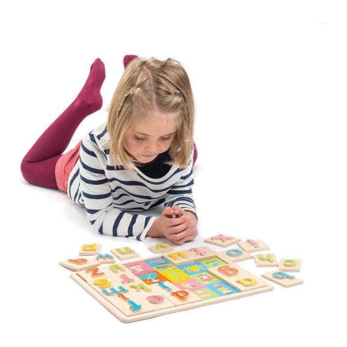 girl lying on floor playing with Tender Leaf Alphabet Pictures Wooden Toy