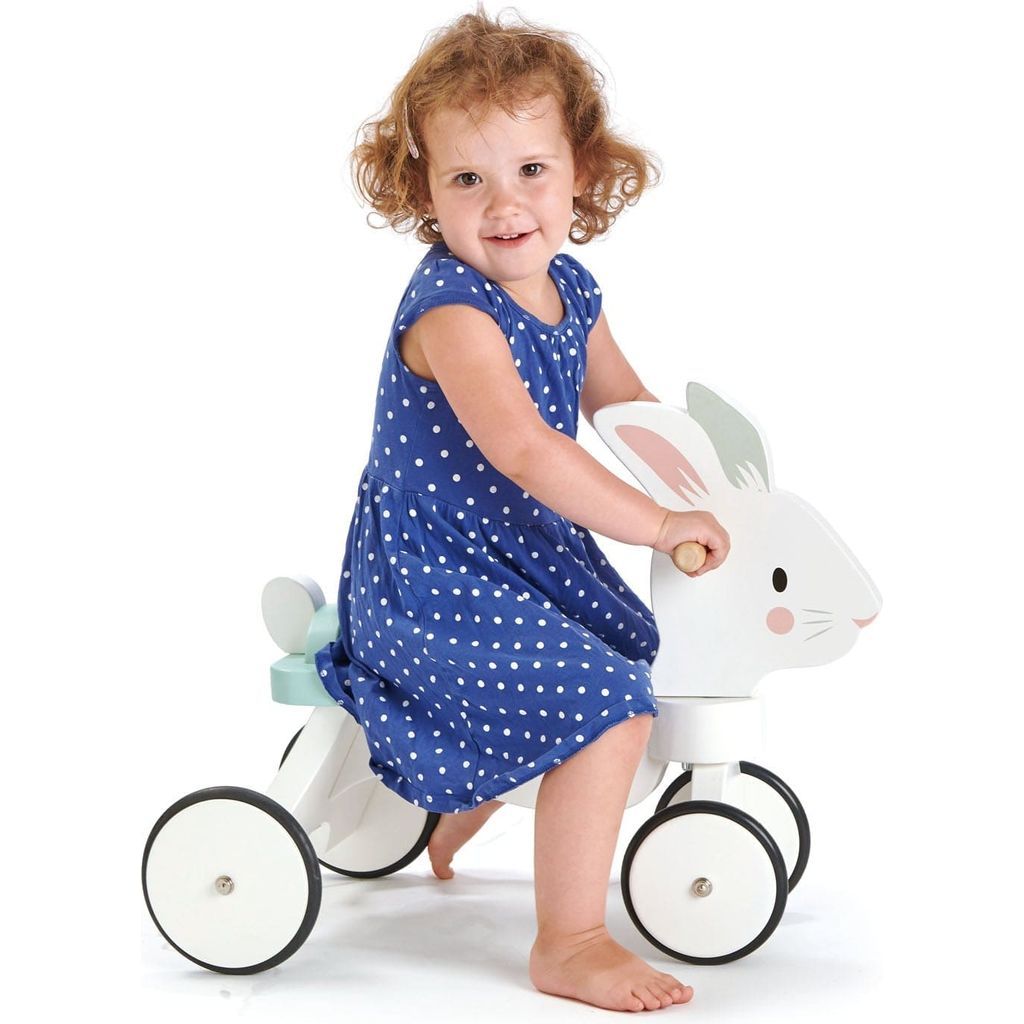 girl in blue dress sitting on Tender Leaf Running Rabbit Wooden Ride On