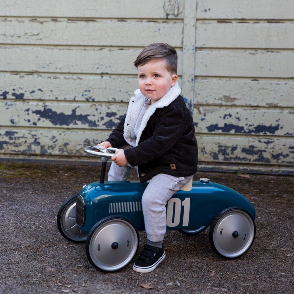 little boy sitting on Vilac Classic Ride-On Racing Car - 18m+ - Petrol Blue