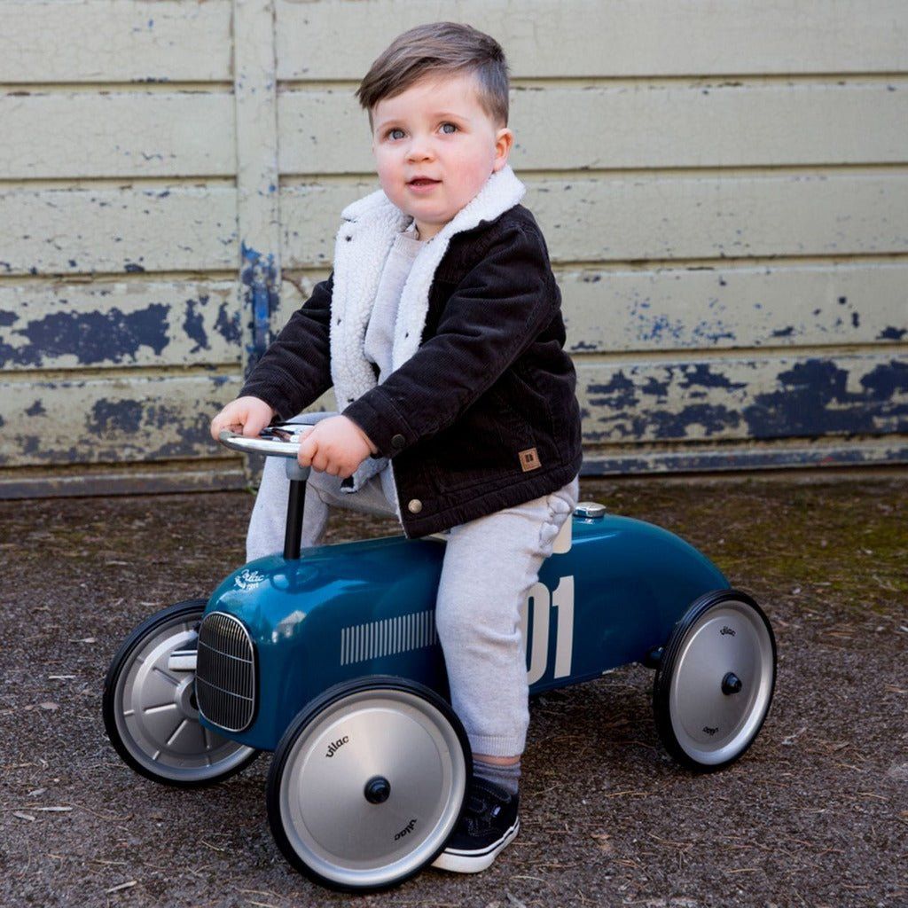 little boy sitting on Vilac Classic Ride-On Racing Car - 18m+ - Petrol Blue
