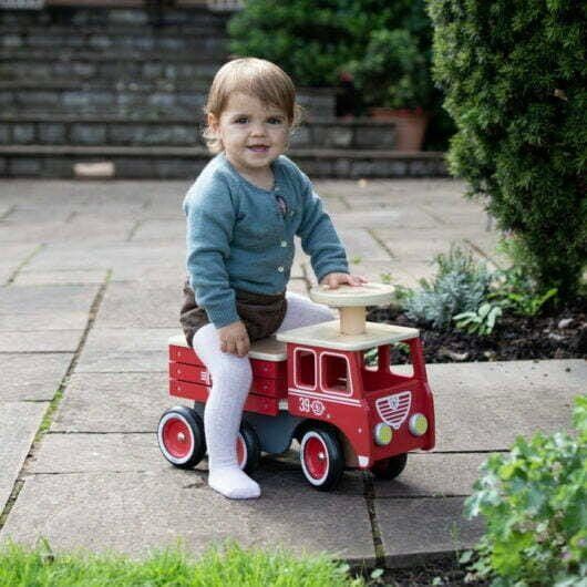 child riding Vilac Ride-On Wooden Firetruck