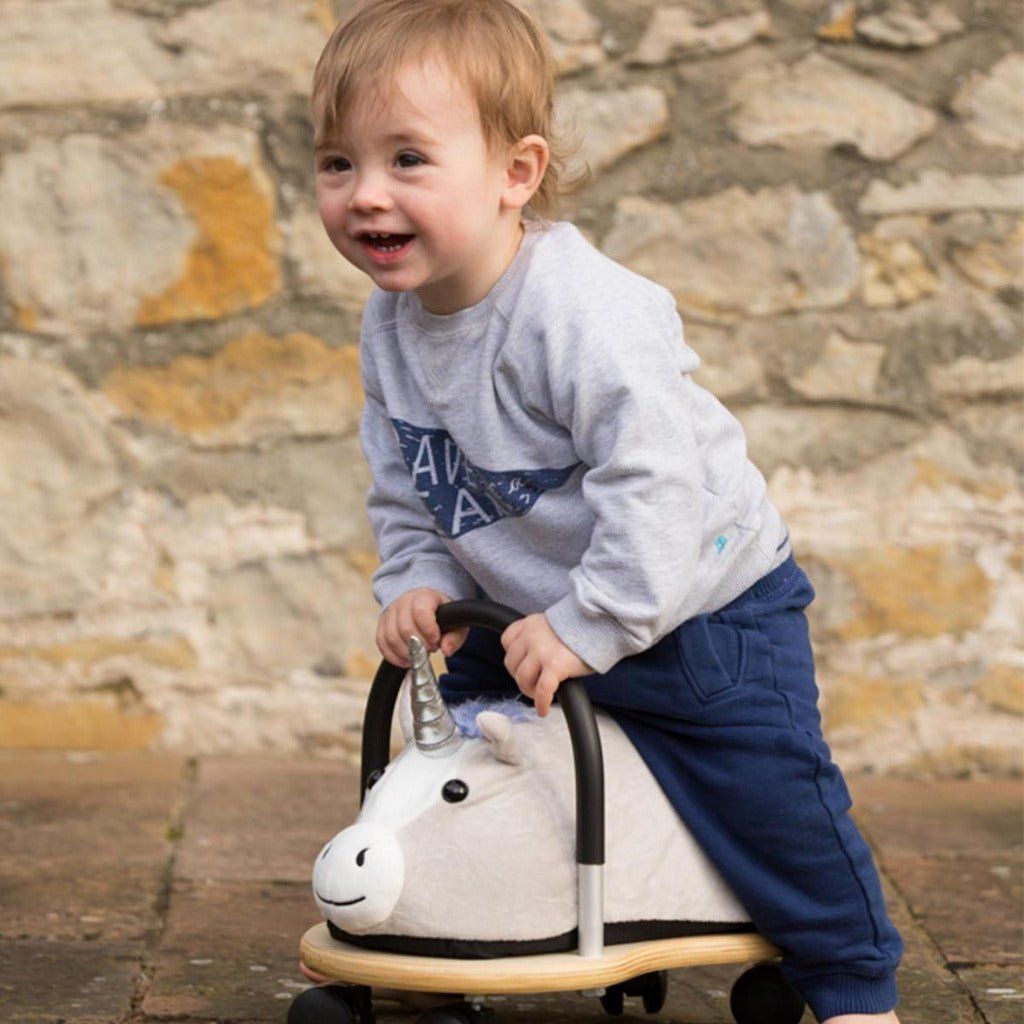 child riding Wheelybug Plush Ride On - Unicorn