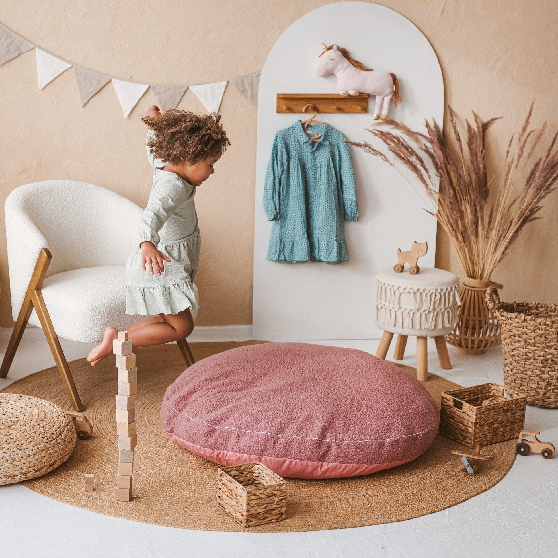 girl jumping onto MINICAMP Boucle Fabric Kids Floor Cushion in Rose