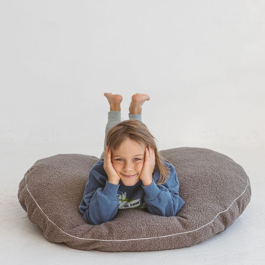child lying on their front on MINICAMP Boucle Fabric Kids Floor Cushion in Grey