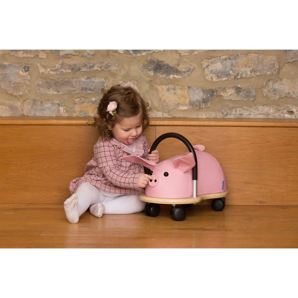 little girl sitting next tp Wheelybug pig Ride On
