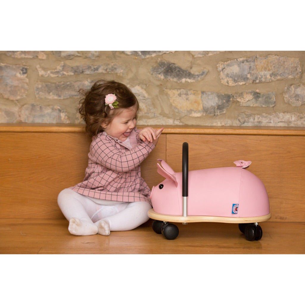 little sitting next to Wheelybug Ride On - Pig