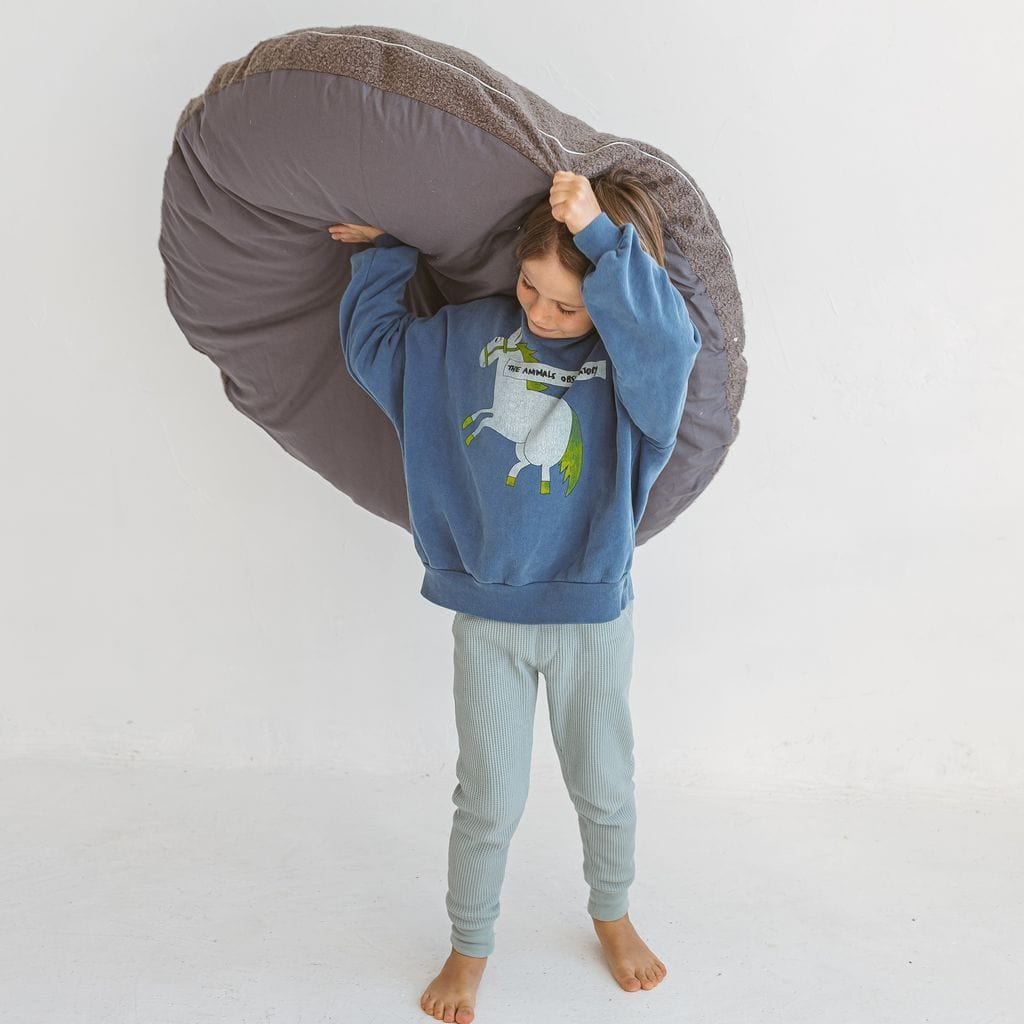 child holding MINICAMP Boucle Fabric Kids Floor Cushion in Grey above head