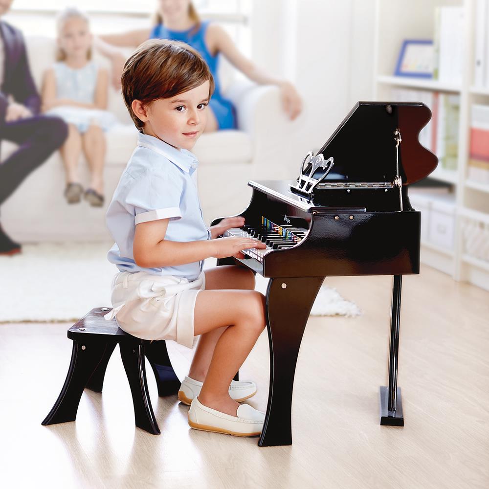 boy sitting at vilac wooden grand piano toy