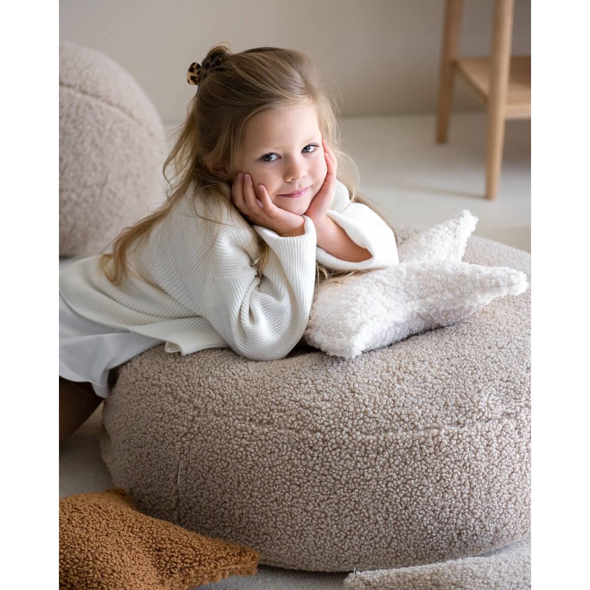 girl resting chin on her hands while leaning on Wigiwama Biscuit Ottoman