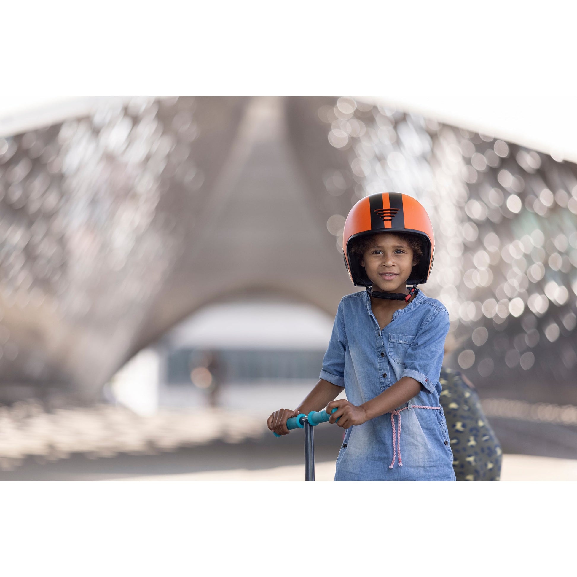 child wearing Chillafish Helmet Bobbi Small Orange standing with scooter