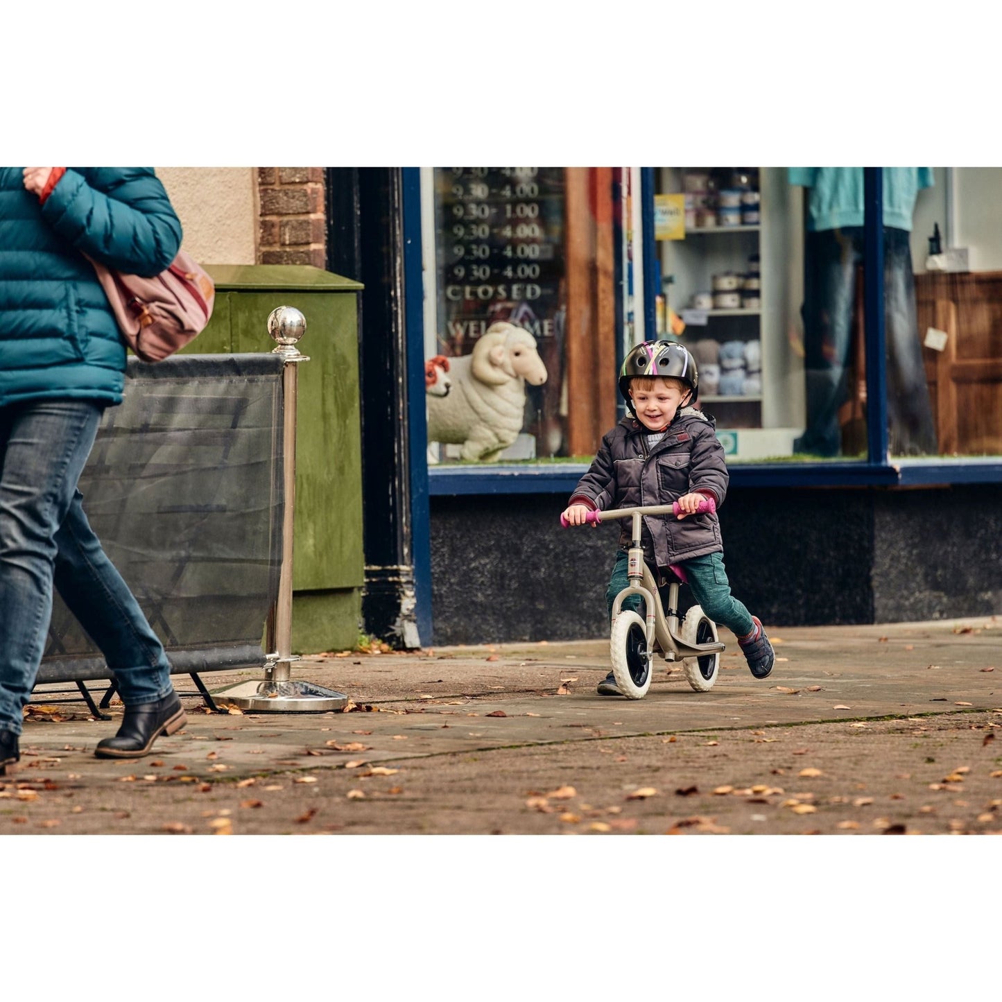 boy ridign Ride-Ezy Go Balance Bike - Pink & Silver in front of shop