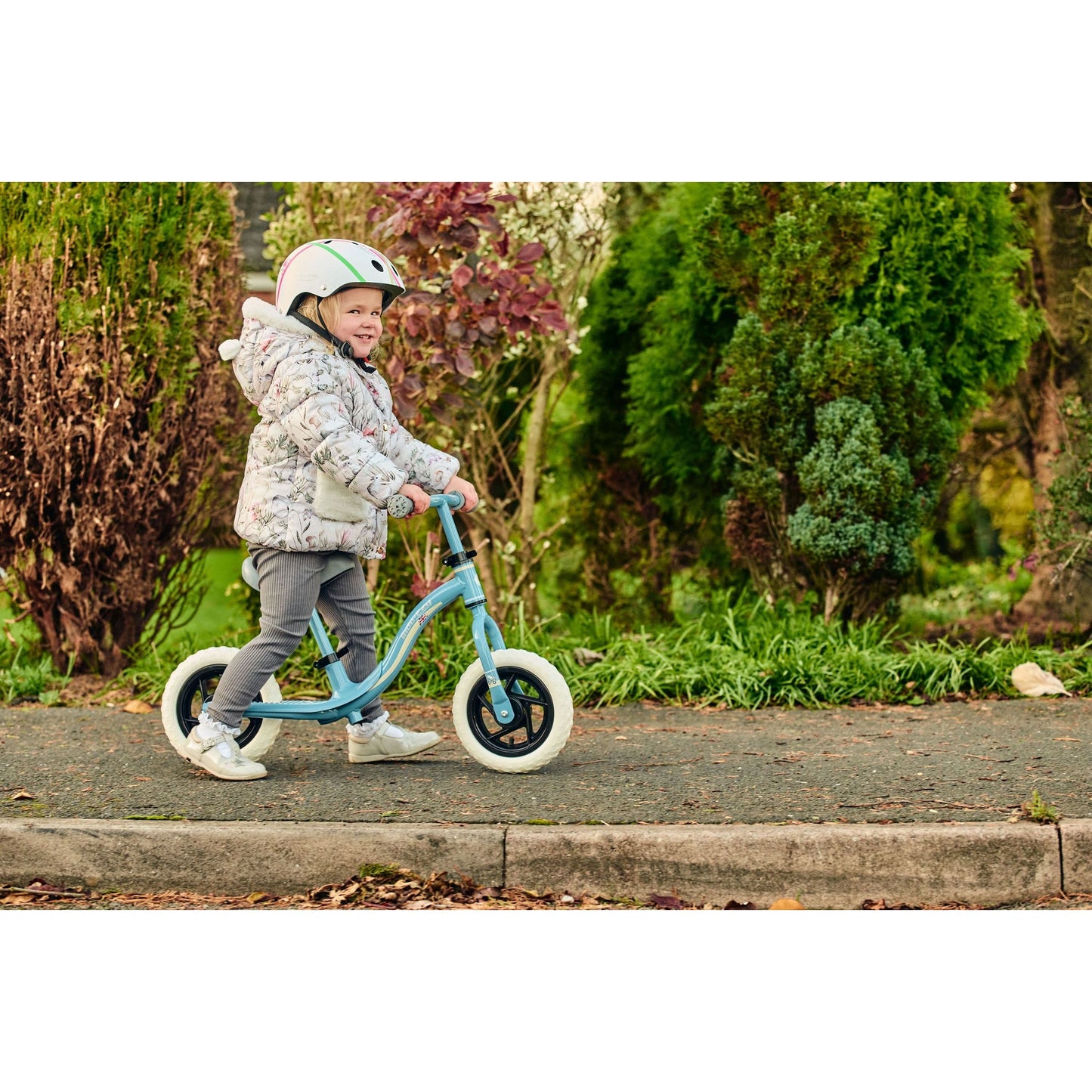 girl wearing Ride-Ezy Hector 54-57cms Kids Helmet - White and riding ride-ezy go glo balance bike