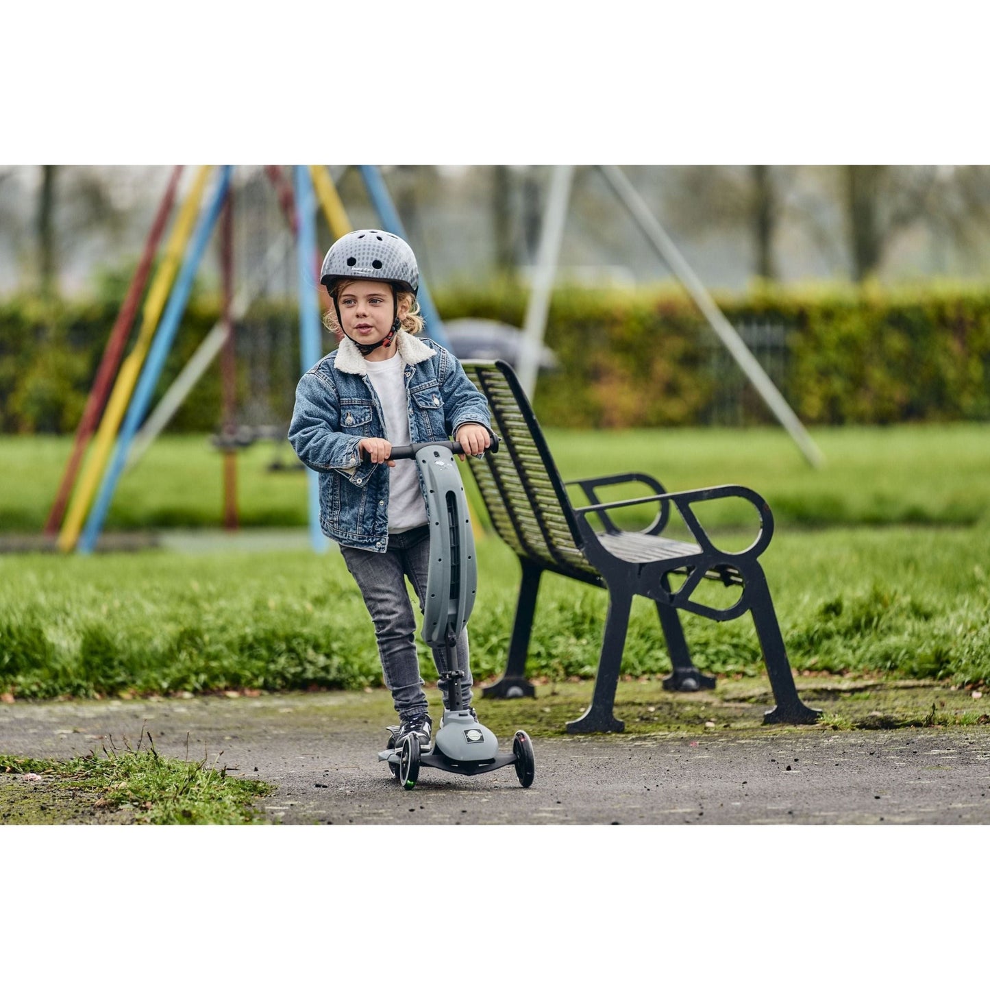 child riding Ride-Ezy Kick & Go Scooter - Thunder Cloud in fornt of bench in the park