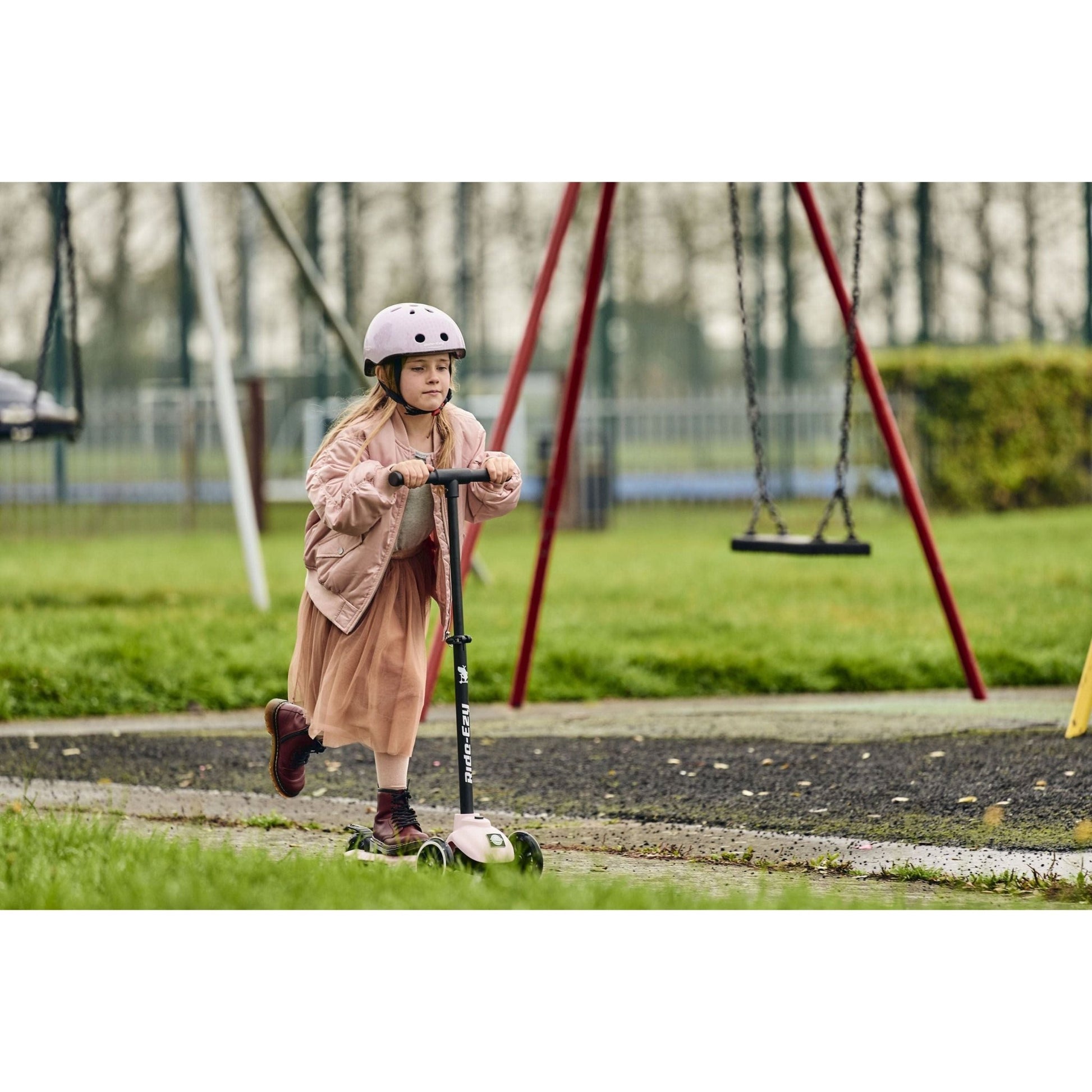 girl riding Ride-Ezy Kick Scooter - Blossom near swings in park