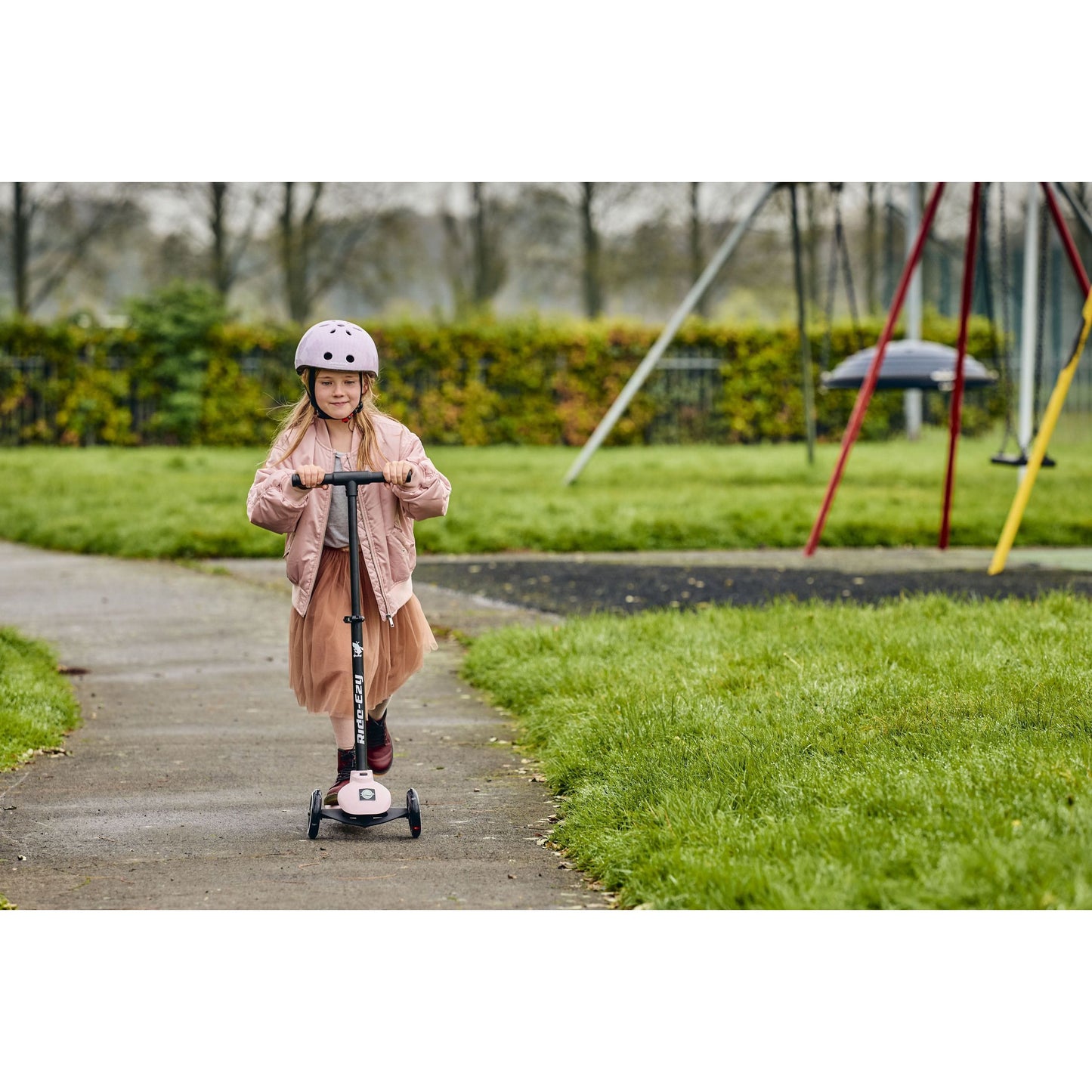 girl riding Ride-Ezy Kick Scooter - Blossom near swings in park