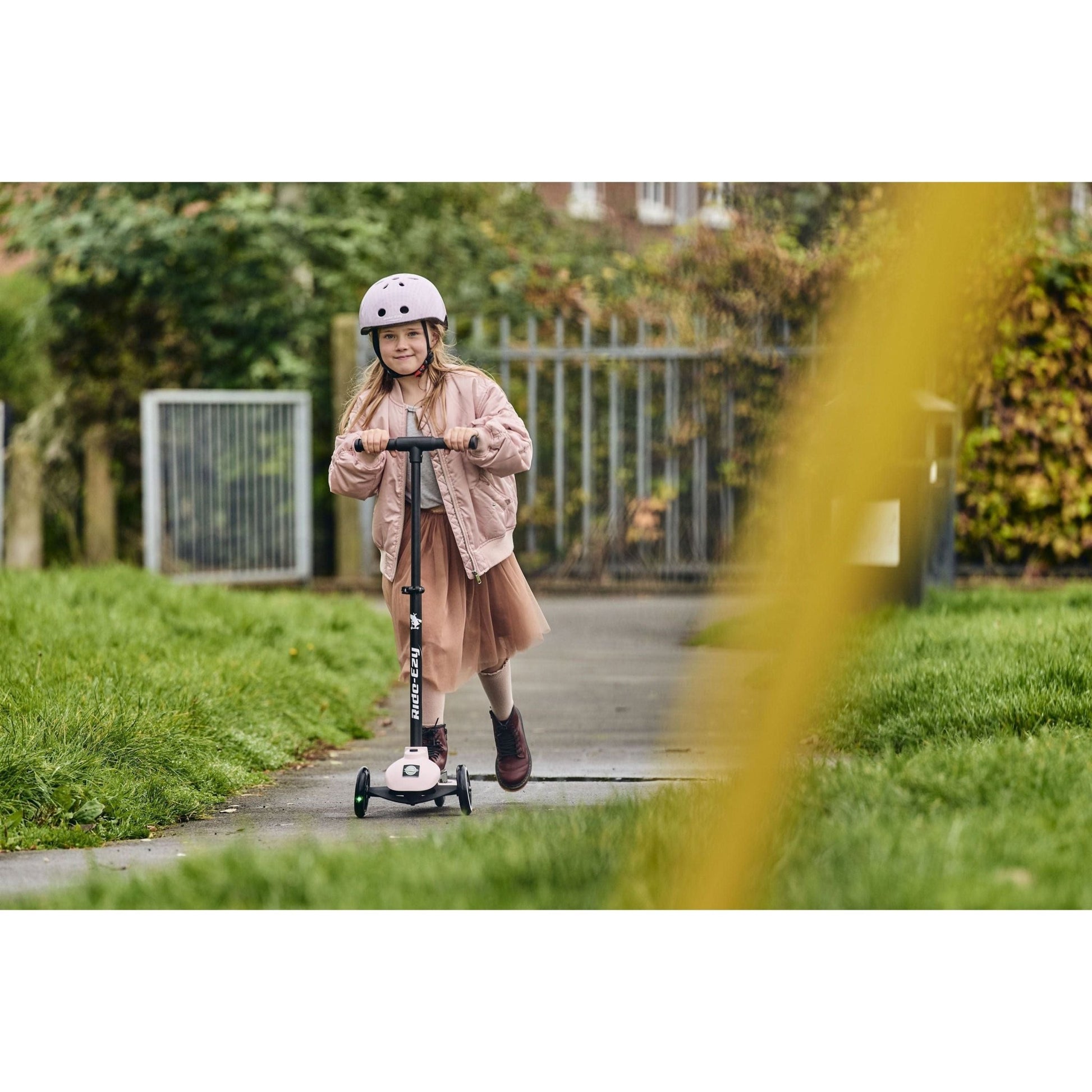 smiling girl riding Ride-Ezy Kick Scooter - Blossom on pathway