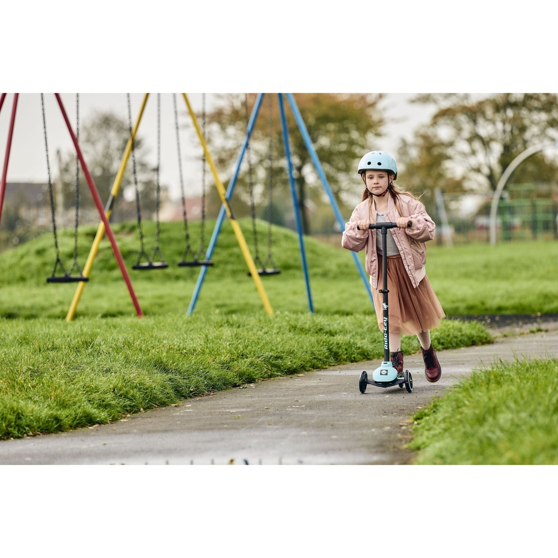 girl riding Ride-Ezy Kick Scooter - Kingfisher in park near swings